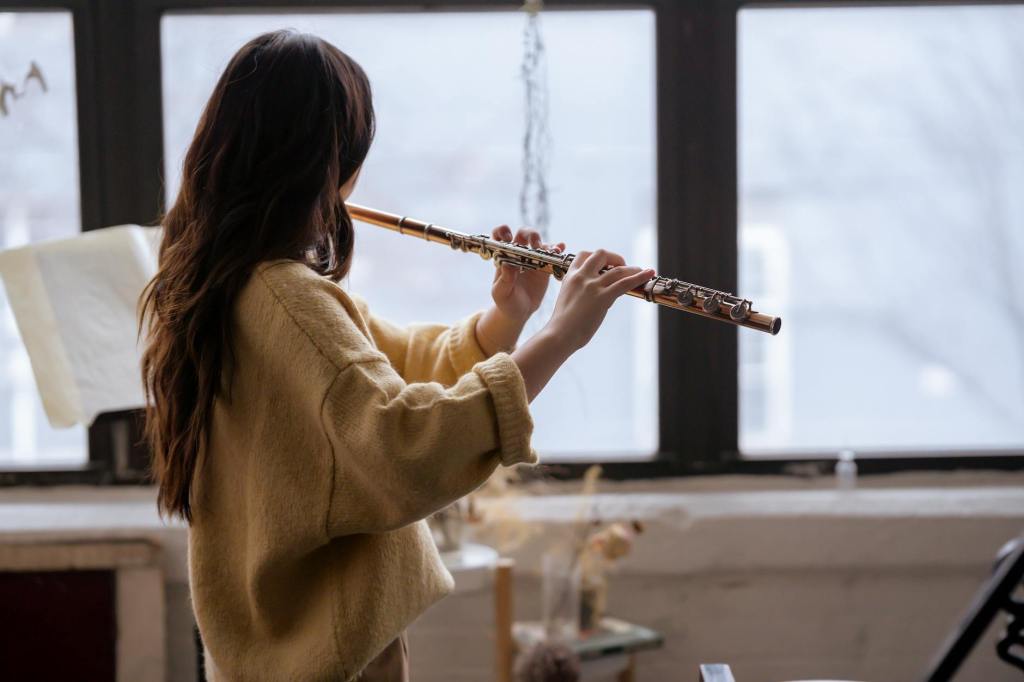 The silhouette of an adult playing the flute in a peaceful room